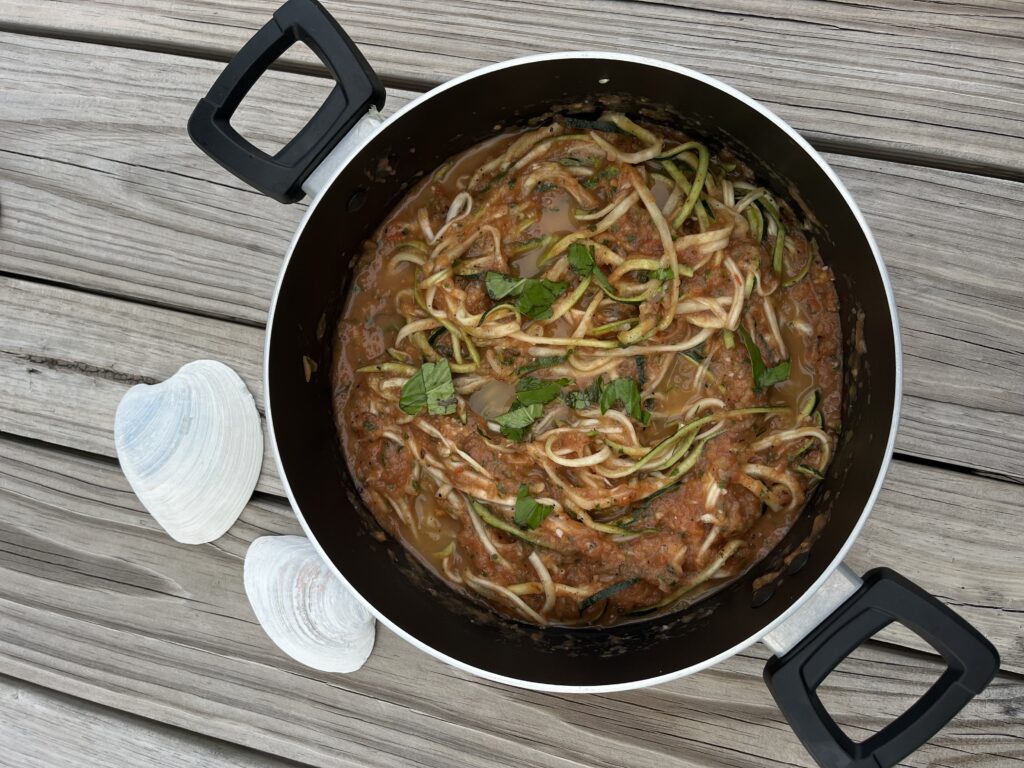 a pot of zucchini noodles and fresh tomato sauce on a picnic table